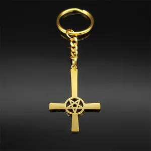 Detailed view of golden inverted cross and pentagram keychain on reflective black surface