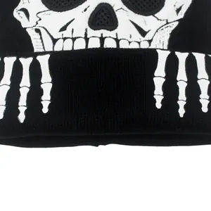 Détail du bonnet en tricot noir avec motif de crâne blanc et mains de squelette imprimées