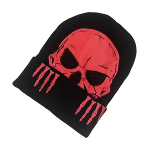Détail d'un bonnet en maille noire avec motif tête de mort et mains de squelette