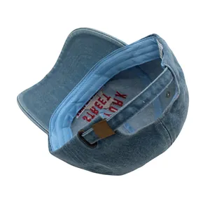 Détail de la casquette en jean bleu avec boucle en métal et broderie New York à l'intérieur