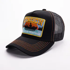 Close-up of STATION embroidery and orange contrast stitching on black mesh trucker hat