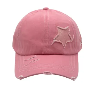 Detail of pink washed cotton baseball cap with sequined star patch and distressed edges