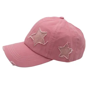 Detailed shot of pink distressed baseball cap featuring glitter star patches and contrast stitching