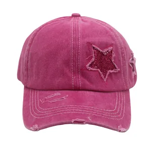 Detail of rose red washed cotton baseball cap with distressed holes and glitter star