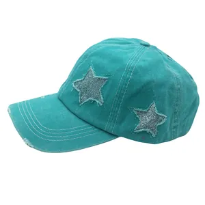 Close-up of distressed washed cotton turquoise baseball cap with glittery star patches