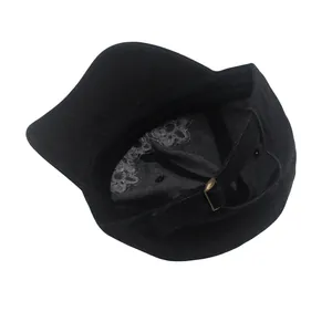 Détail de la casquette en denim noir montrant la boucle en métal et la doublure fleurie