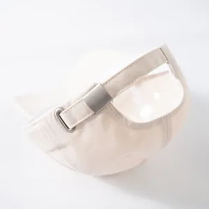 Detail view of cotton baseball cap with adjustable matte metal buckle on beige fabric