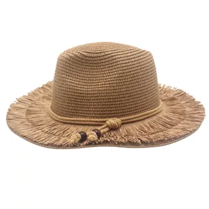 Detail of khaki straw sun hat featuring frayed tassel brim and braided rope with wood beads