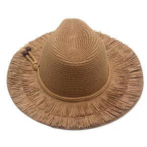 Detailed macro view of wide brim straw sun hat featuring fringe edges and decorative beads