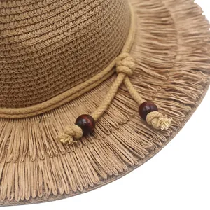 Close-up of bohemian straw hat showing natural fringe brim and wooden bead details