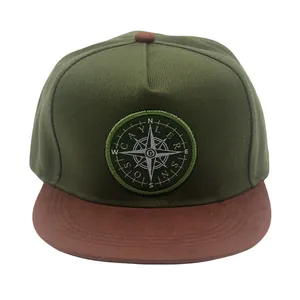Close-up of compass embroidery patch on olive and brown flat brim hip hop cap