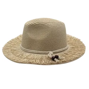 Detail of straw sun hat featuring frayed tassel brim and white rope with wooden beads