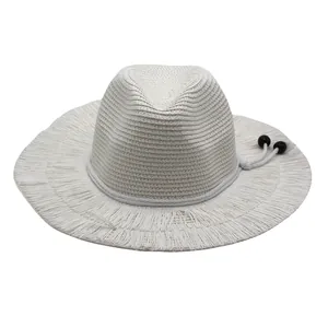 Detail of white straw sun hat featuring a wide fringe brim and woven rope with dark beads