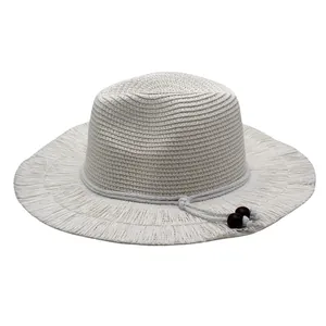 Detail of hand-woven straw hat with wide brim, ivory tassels and decorative brown beads