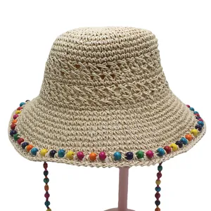 Détail du chapeau de paille tressé main avec perles en bois colorées et texture