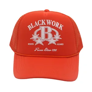 Detail of the white B letter and Black Work print on an orange mesh trucker hat