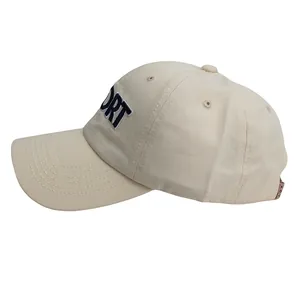 Close-up of beige cotton baseball cap with blue SPORT embroidery and side profile details