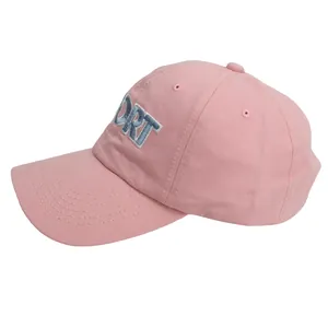 Close-up of pink cotton baseball cap with blue PORT letter embroidery and curved visor