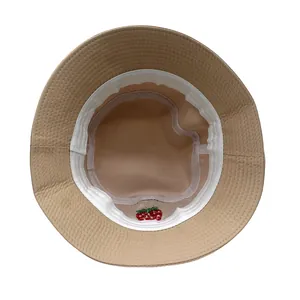 Dettaglio dell'interno del cappello a secchiello kaki con ricamo a fragola e fascia interna
