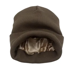 Detalle del gorro de punto marrón mostrando el forro interior de satén suave color oro