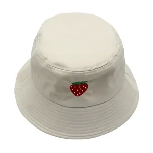 Dettaglio del ricamo a fragola su un cappello a secchiello in tela di cotone crema
