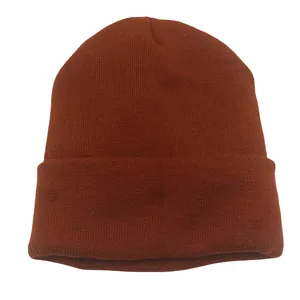 Detalle del gorro rojo óxido que muestra la textura de punto acanalado y el borde doblado
