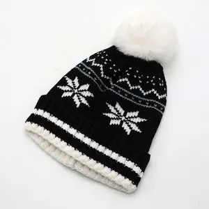 Détail du bonnet en tricot avec motif de flocon de neige et pompon blanc pelucheux