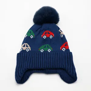 Detail of baby winter knit hat with colorful car patterns and soft faux fur pompom