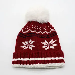 Détail d'un bonnet en maille d'hiver avec pompon blanc et motifs de flocons de neige