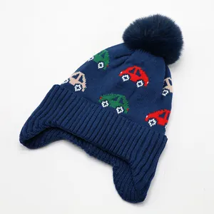 Detail of knitted car pattern and fluffy pom-pom on toddler winter fleece-lined hat