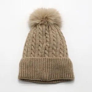 Detailed cable knit pattern on warm winter beanie with a fluffy faux fur pom-pom topper