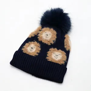 Detail of navy knit hat showing soft pom-pom and cute lion patches with ribbed texture