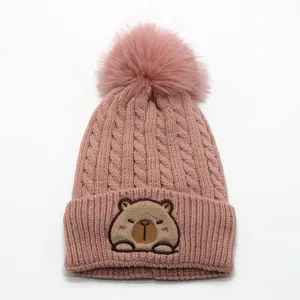 Pink knit beanie for kids featuring a cute capybara embroidery and large faux fur pompom