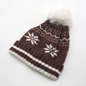 Détail de la maille et pompon blanc sur bonnet d'hiver avec motifs de flocons