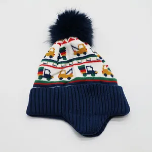 Detailaufnahme der gestrickten Wintermütze mit bunten Baufahrzeug-Mustern und Bommel