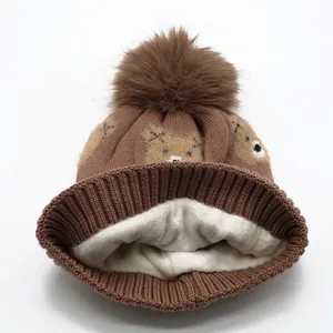 Brown knitted children's winter hat with fluffy pompom and thick warm fleece lining