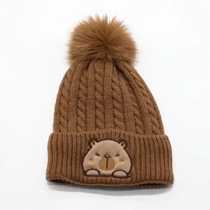 Brown knit beanie with large pom-pom and cute capybara patch for kids winter warmth