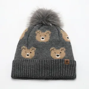 Grey knit kids beanie with cute bear patterns and a large fluffy faux fur pom-pom