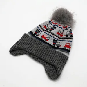 Kinder-Strickmütze mit Ohrenklappen, Baustellen-Motiven und einem grauen Kunstfell-Pompon