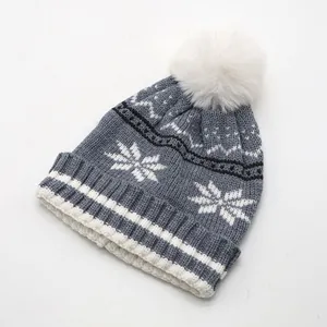 Détail du tricot de ce bonnet d'hiver gris pour enfant avec flocon et pompon blanc