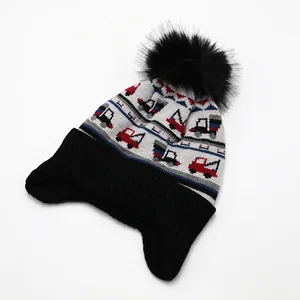 Detailaufnahme der Kinderstrickmütze mit Jacquard-LKW-Mustern und schwarzem Kunstfellbommel