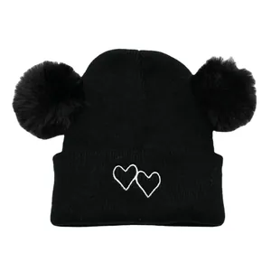 Kids black knit beanie featuring double pom poms and embroidered white hearts