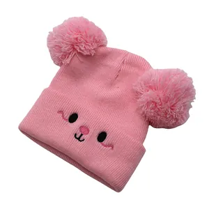 Detailed knit texture and cute embroidered cartoon face on a pink winter hat for kids