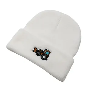 Gros plan d'un bonnet blanc tricoté pour bébé avec broderie de pelleteuse sur le revers