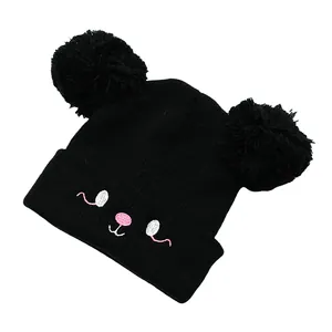 Detailed view of black knitted kids hat with large pom-poms and cute animal embroidery
