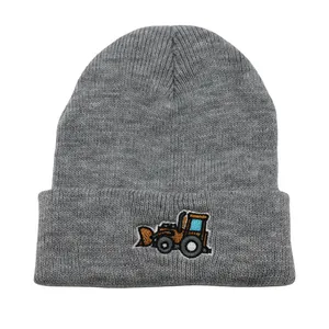 Détail de la broderie de bulldozer sur le bonnet en tricot gris à revers pour enfants