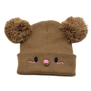 Detail of cute bear-ear pom-poms and embroidered animal face on brown knit hat