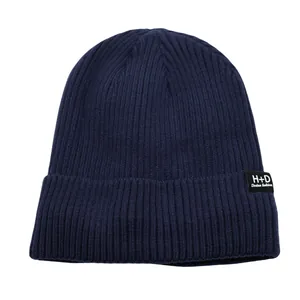 Gros plan du bonnet en tricot bleu marine avec l'écusson H+D Desian fashion