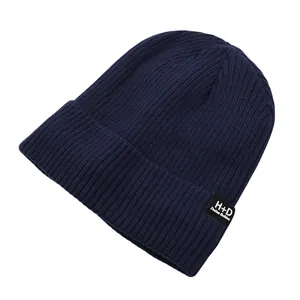 Détail du bonnet en tricot bleu marine avec un écusson tissé carré noir et logo blanc