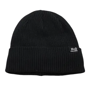 Gros plan du bonnet en maille côtelée noire avec texture épaisse et écusson H+D logo
